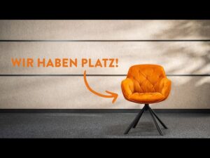 meinkarrierestart.at Auf einem dunklen Boden vor einer beigen Wand steht ein orangefarbener Polsterstuhl mit dem deutschen Text „WIR HABEN PLATZ!“ und einem Pfeil, der auf den Stuhl zeigt.